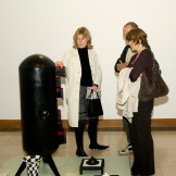 Visitors looking at Hamed Ouattara's Soundiata. Chest of drawers, black metal sheet and welded frying pans.